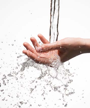 Closeup woman hand under the stream of splashing water - skin care concept